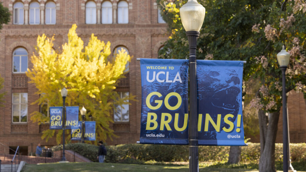 Trump’s UCLA deal: Pay us $1B+, and we can still cut your grants again Image of a UCLA banner in front of brick buildings on a campus.