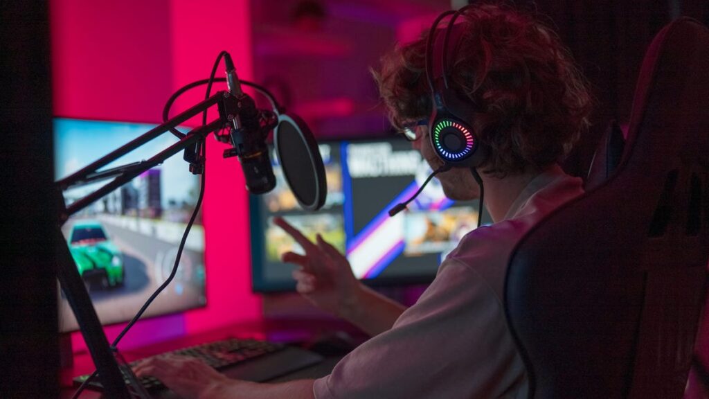 Twitch gamer in front of two screens playing and gesturing with hand
