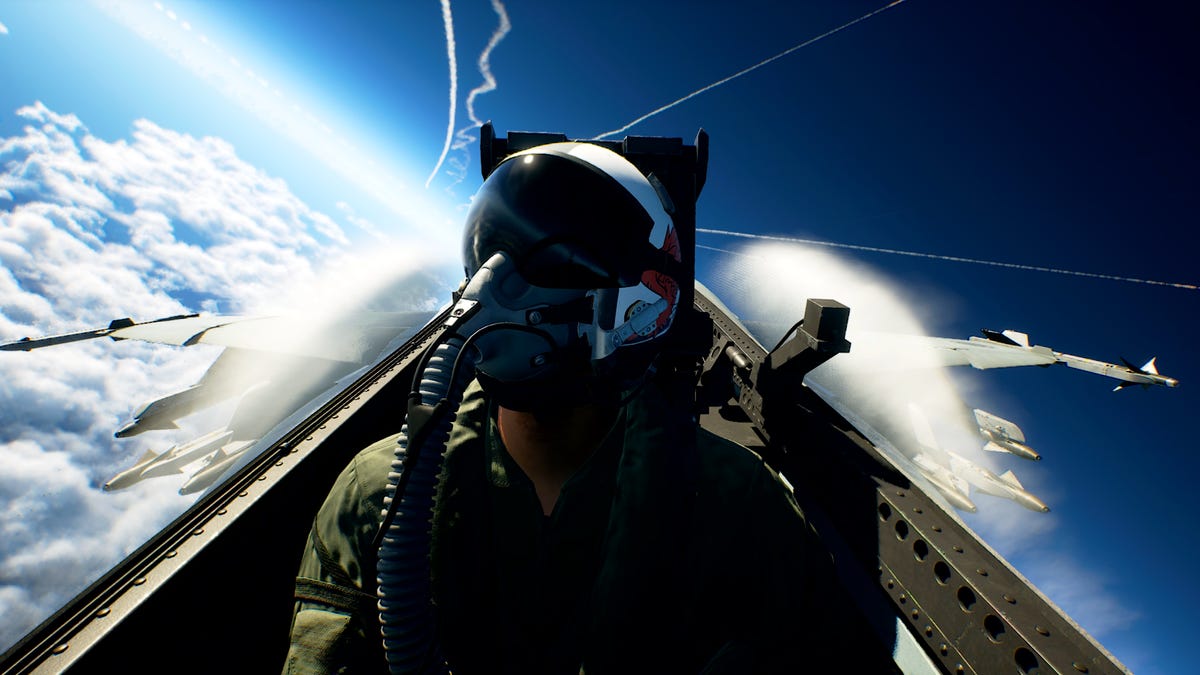 In a screenshot is a pilot with mask on in the cockpit of a fighter jet with clouds and the horizon behind the jet.