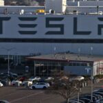 Aerial view of a Tesla factory showing the parking lot and exterior