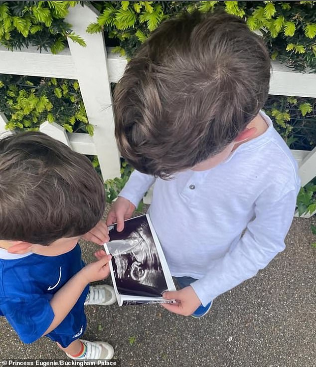 In a photograph shared by Princess Eugenie today, Ernest, wearing a Chelsea football kit, and August, wearing a long-sleeved grey T-shirt, can be seen holding a picture of a baby scan