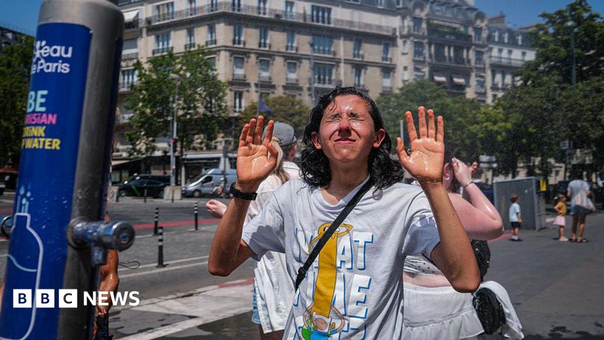 People cool off beneath a misting station during hot weather on June 24, 2026 in Paris, France.