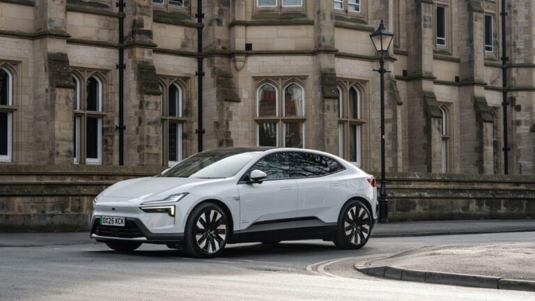 A white Polestar 4 vehicle is parked next to a building on a curved roadway.