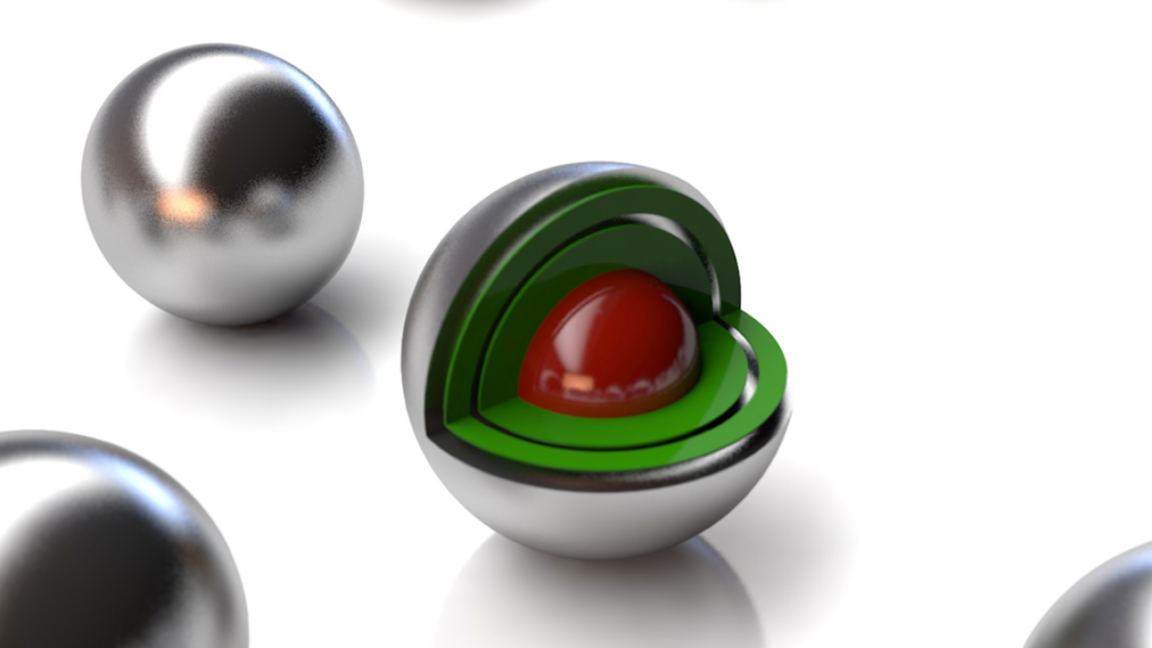 Image of a set of silvery balls, one of which has a cutaway showing layers of green and a red core.