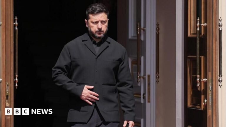 Zelensky, wearing a dark suit, walking through a doorway