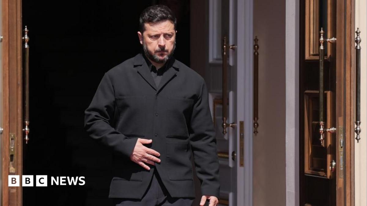 Zelensky, wearing a dark suit, walking through a doorway