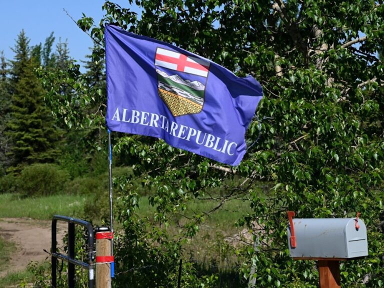 A blue flag with the Alberta crest and the words ‘Alberta Republic’ flies on a short pole attached to a gate.