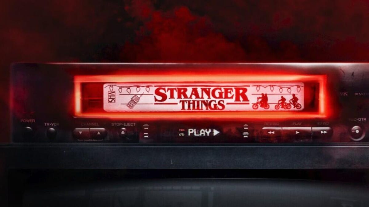 VHS tape in a VCR with Stranger Things logo aside string of lights, illustrations of kids on bikes.