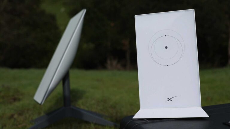 Picture of a Starlink satellite dish and router placed outside, on a lawn.