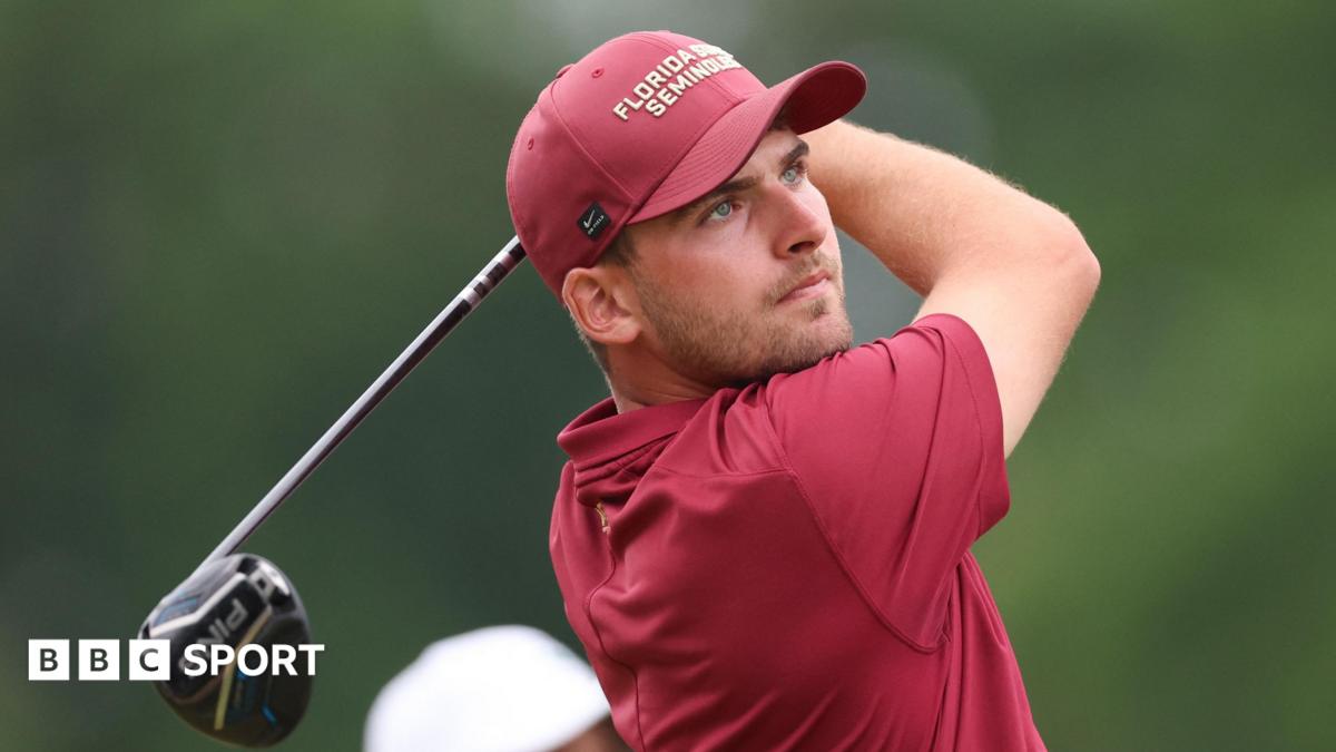 Jack Whaley, in red golf shirt and cap, tees off and watches his shot