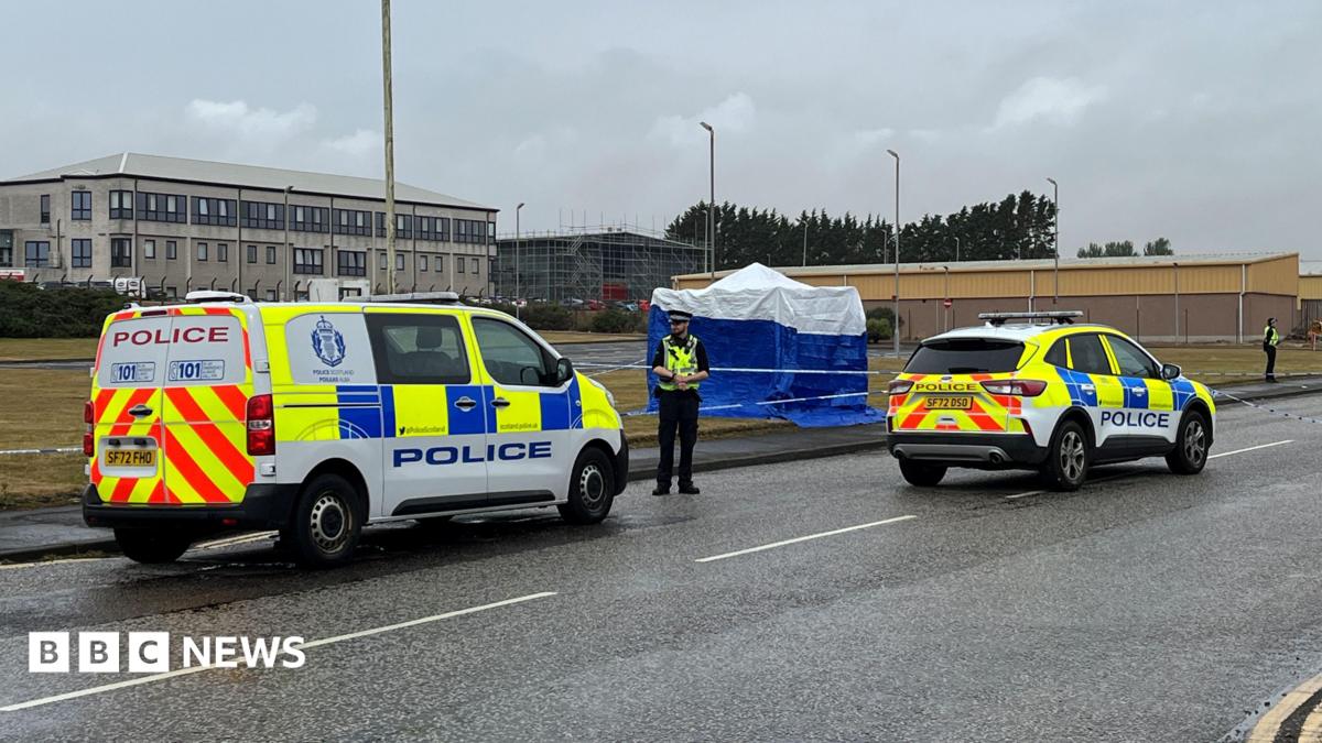 a police van, car and two officers in the road outside an industrial estate