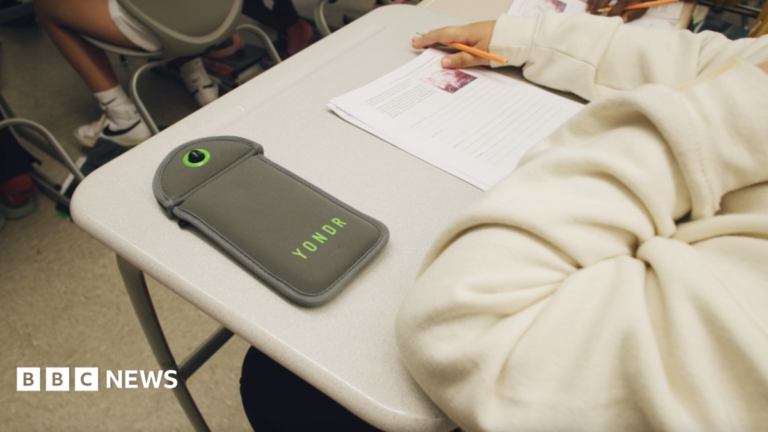 A Yondr pouch on the desk as a child sits a test.