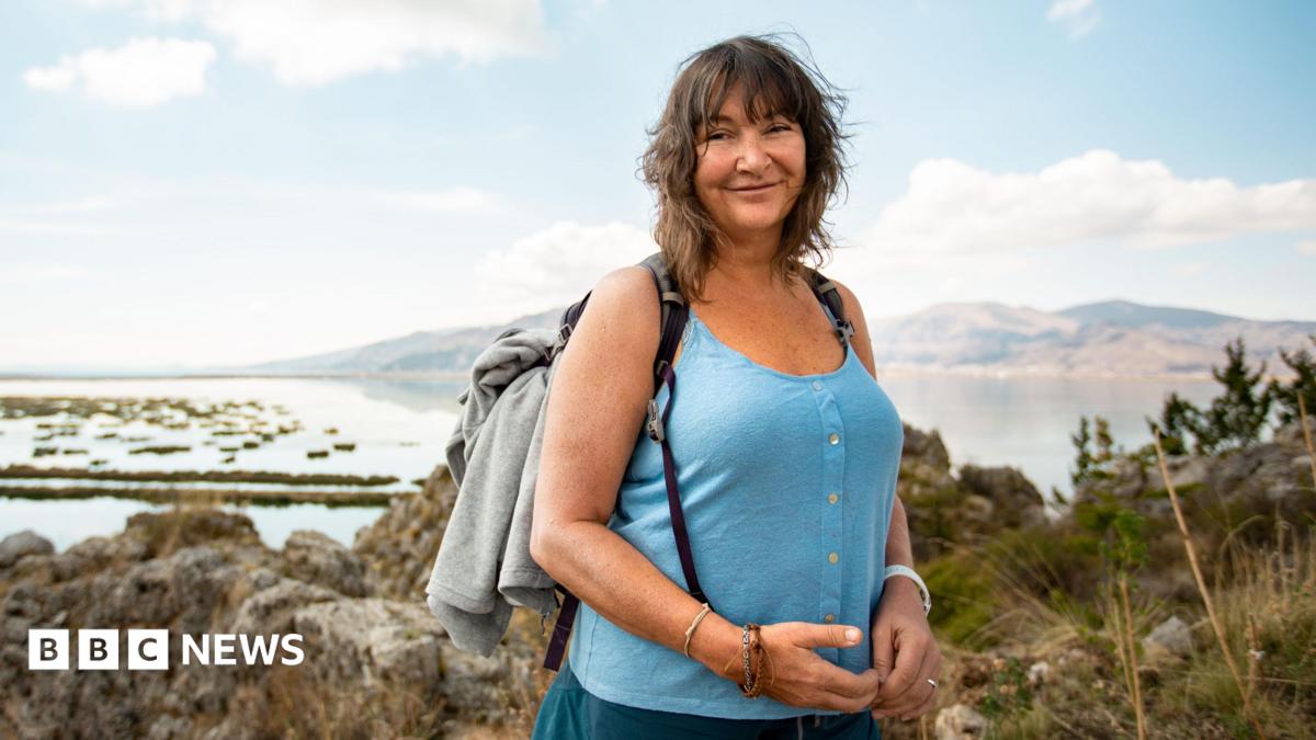 Woman in blue vest and shorts wearing a grey rucksack
