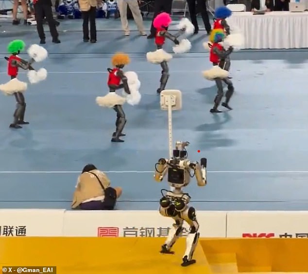 At the start of the video, five humanoid robots can be seen performing a cheerleading routine – complete with colourful wigs, short skirts and pom–poms