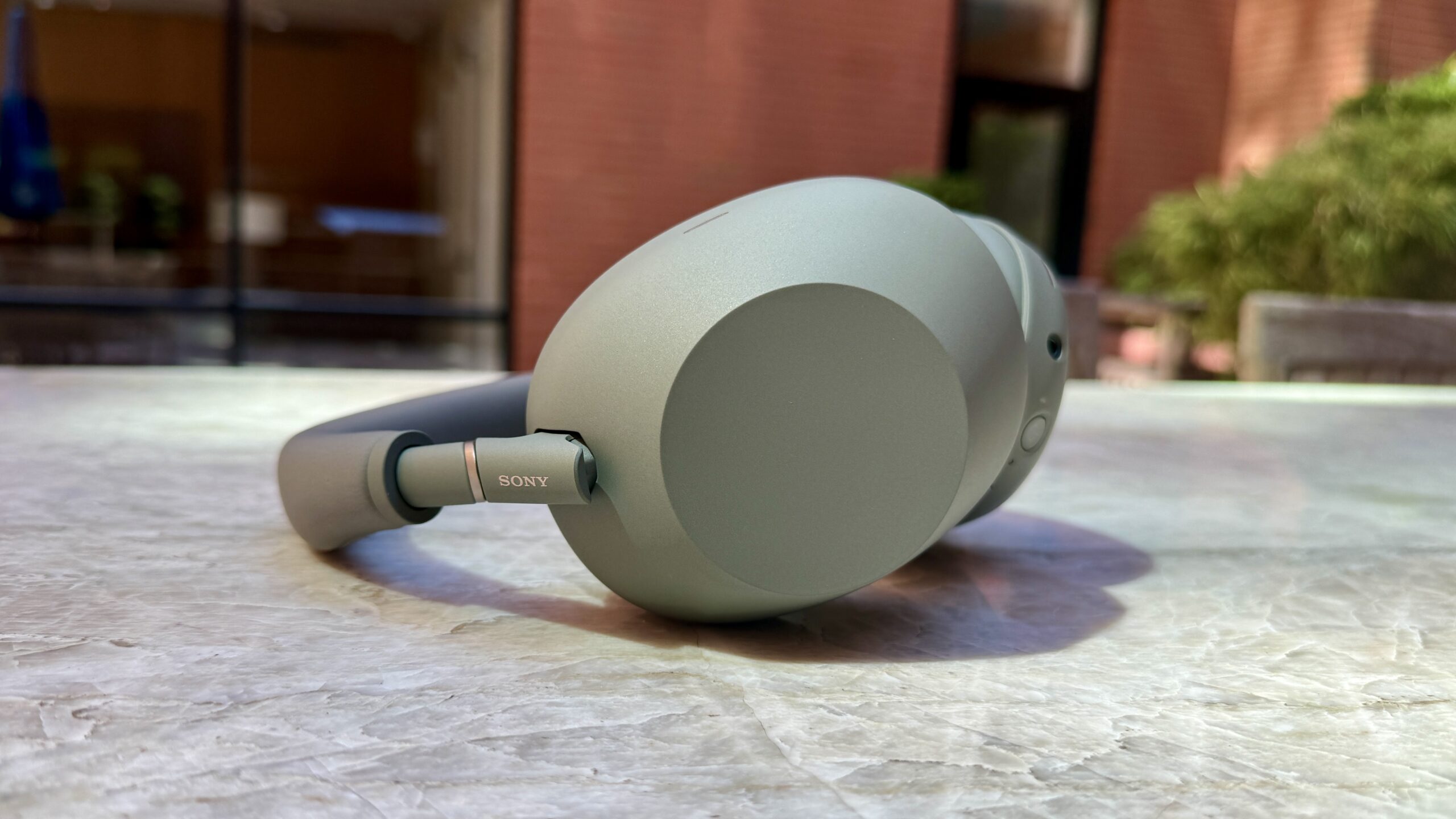 Sony WH-1000XM6 in olive gray sitting on marble countertop