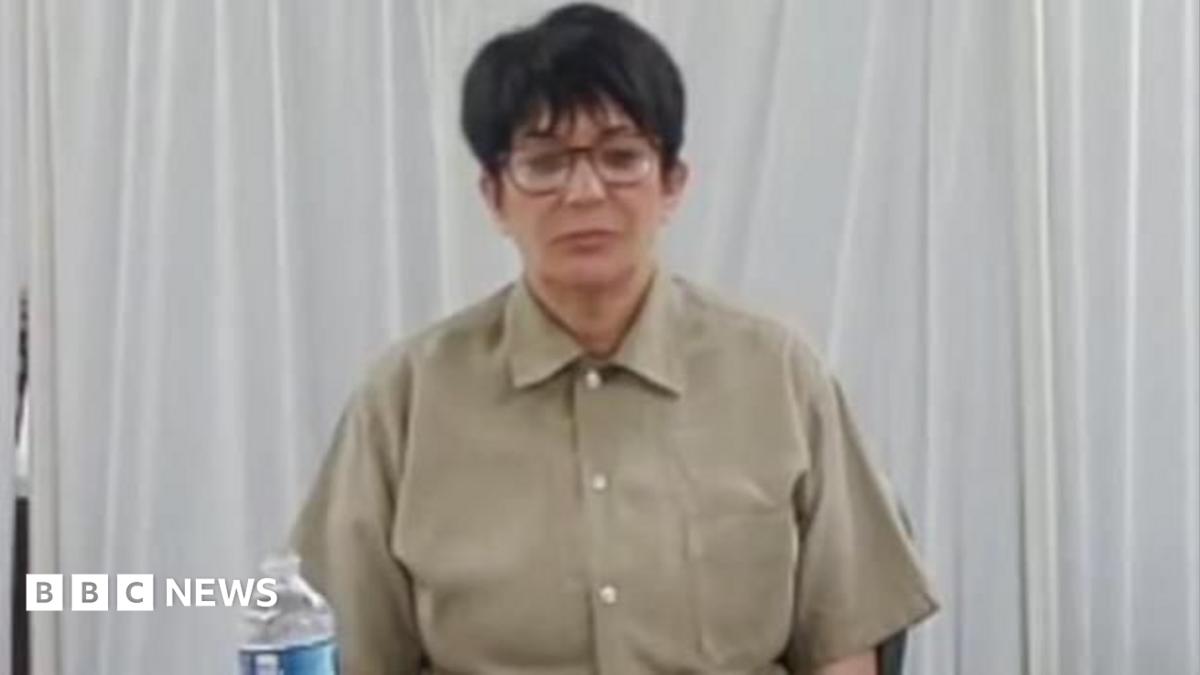 Ghislaine Maxwell sits in a tan shirt with a water visible in front of her.