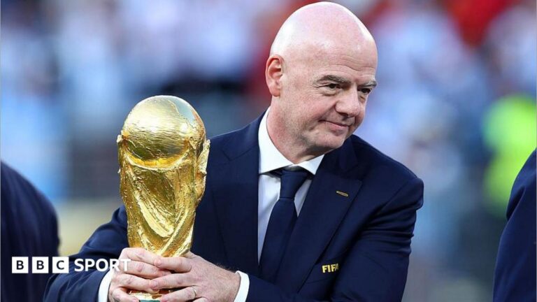 Gianni Infantino with his hands around the men's World Cup trophy