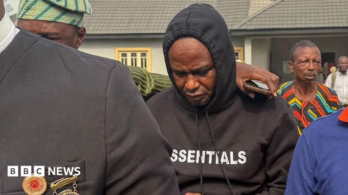 Adeniyi Mobolaji Kayode is in a black hoody with his head bowed as someone has their arm round him as he is led from court in a picture taken in January 20 this year
