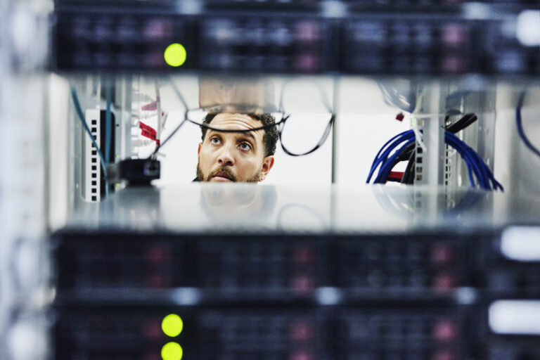 looking through server rack of male IT professional working in data center