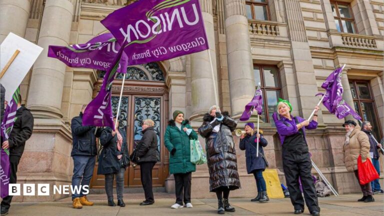 a group of workers protesting and waving purple 'Unison' flags outside an Glasgow City chambers.