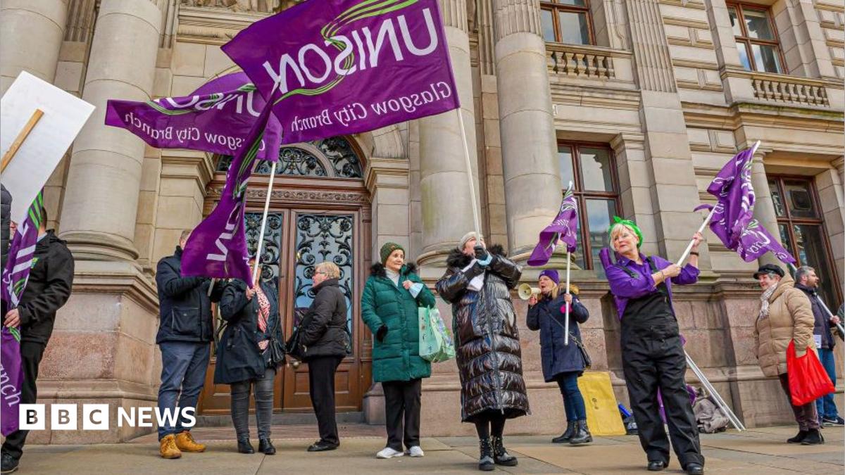 a group of workers protesting and waving purple 'Unison' flags outside an Glasgow City chambers.
