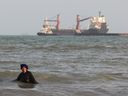 FILE: An Iranian woman enjoys a dip in the sea as vessels are seen in the Strait of Hormuz off the port city of Bandar Abbas, in southern Iran on August 10, 2026.