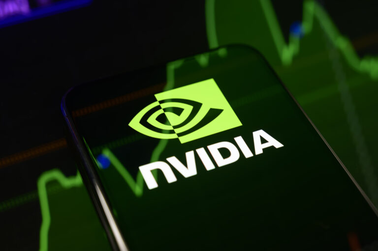 The Nvidia logo displayed on a smartphone screen placed on a reflective surface onto which a stock chart is projected