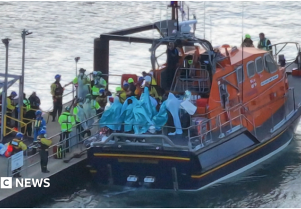 People wrapped in blankets on the back of an RNLI lifeboat moored by a pontoon at Eastney, Portsmouth, on 6.9.26