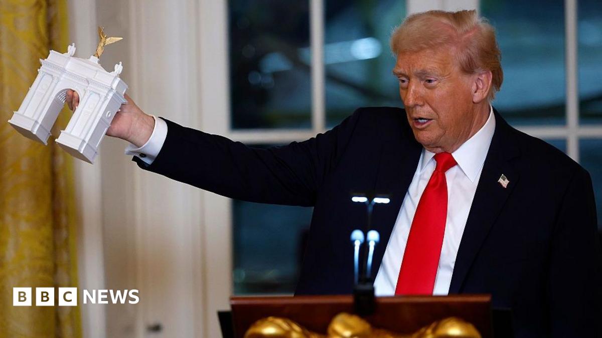Trump holding up a tiny model of a triumphal arch in the White House