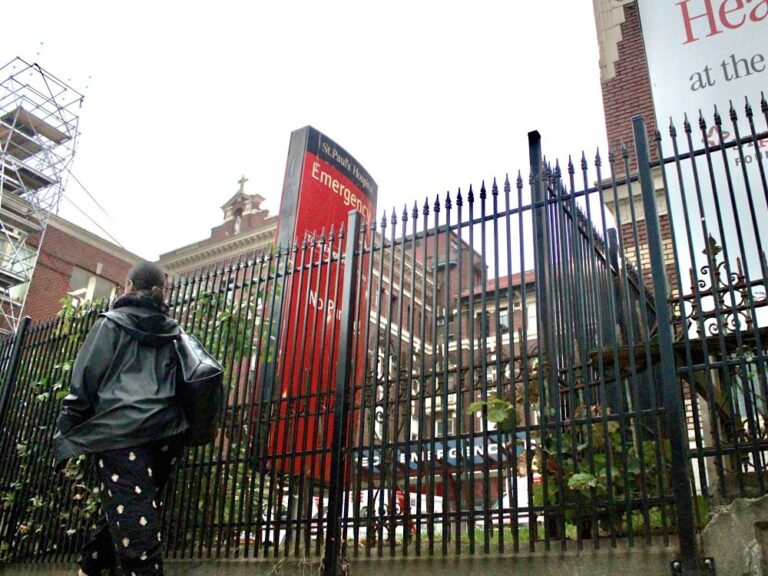 The fence outside St. Paul’s Hospital. A person walks by.