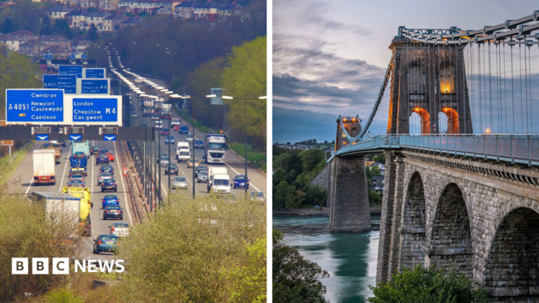 A shot of the M4 on the left, with cars visible on both sides of the motorway, and the Menai Bridge on the right hand side.