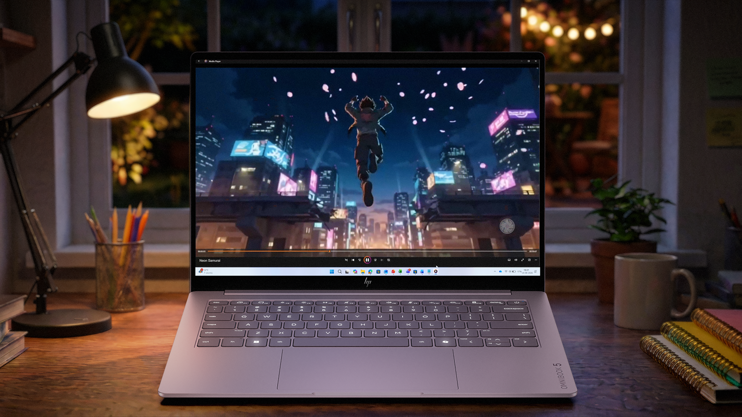 The HP OmniBook 5 14 AI PC sits on a desk with a video playing. A still of a man jumping by rooftops is on the screen.