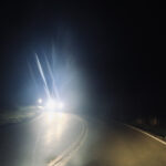 From the perspective of the driver, headlights shine brightly from oncoming traffic at night.