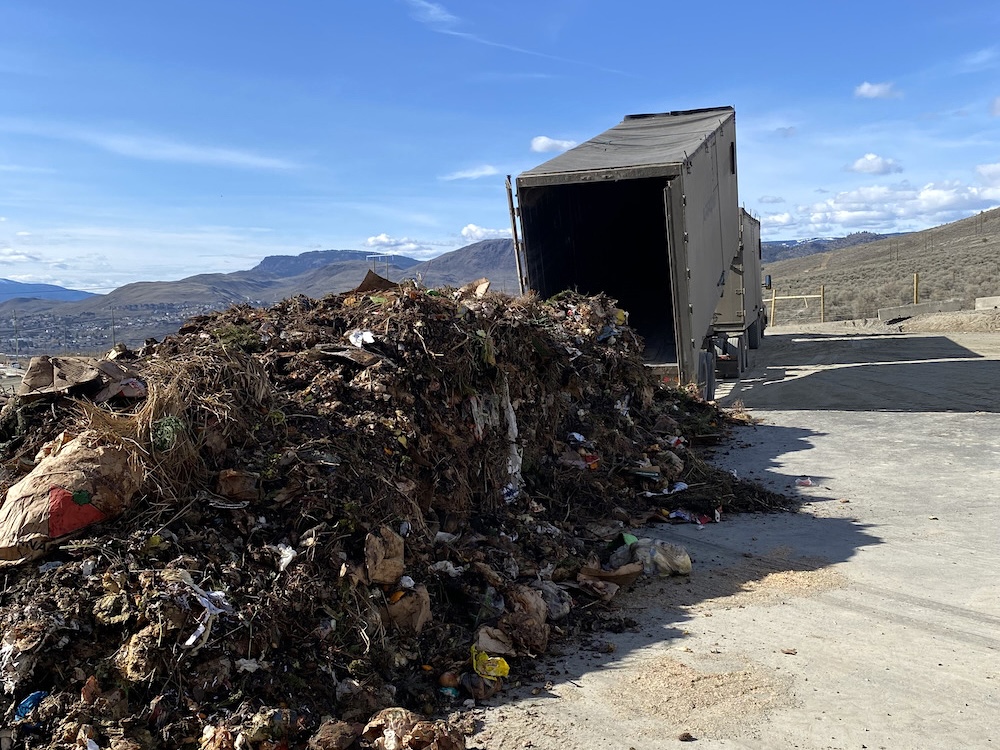 A giant mound of compostable material rests beside a truck at the Stsw&eacute;kstem waste management facility in Kamloops. The brown mound contains pieces of fruit and other compostable material.
